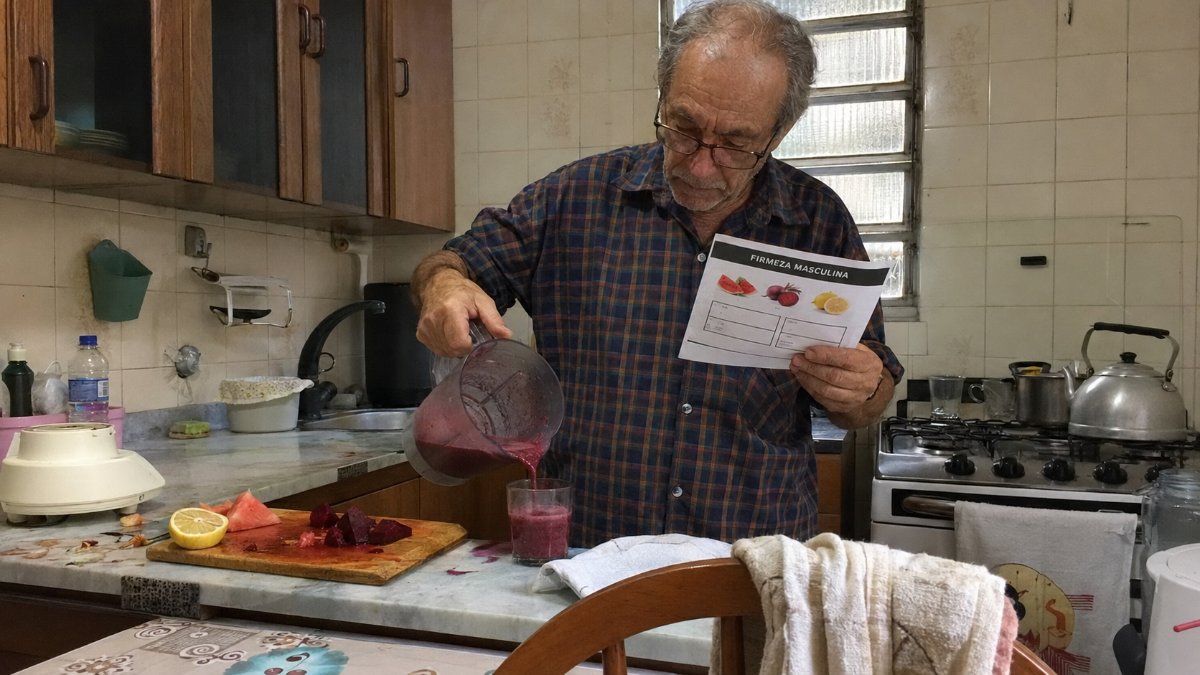 Señor sirviendo la bebida de la receta en un vaso con la guía en la mano