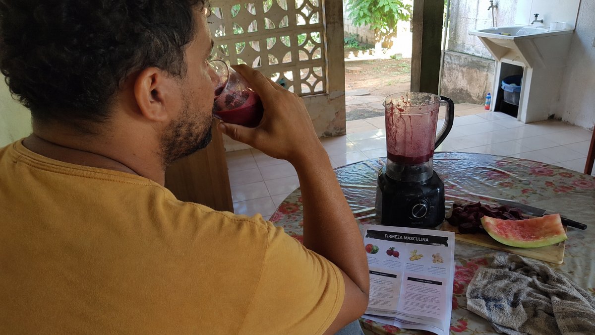 Hombre bebiendo la preparación junto a la licuadora y la guía