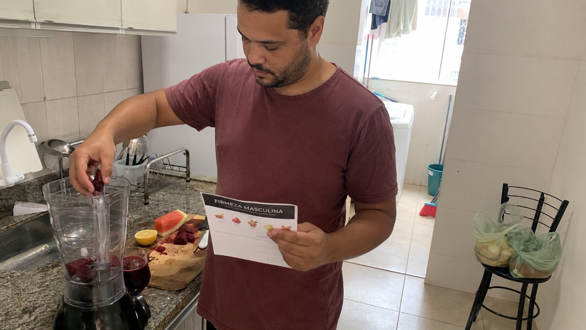 Hombre preparando la receta del ritual en la licuadora siguiendo la guía impresa